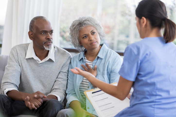 A couple sits and receives information from a doctor sitting opposite them.